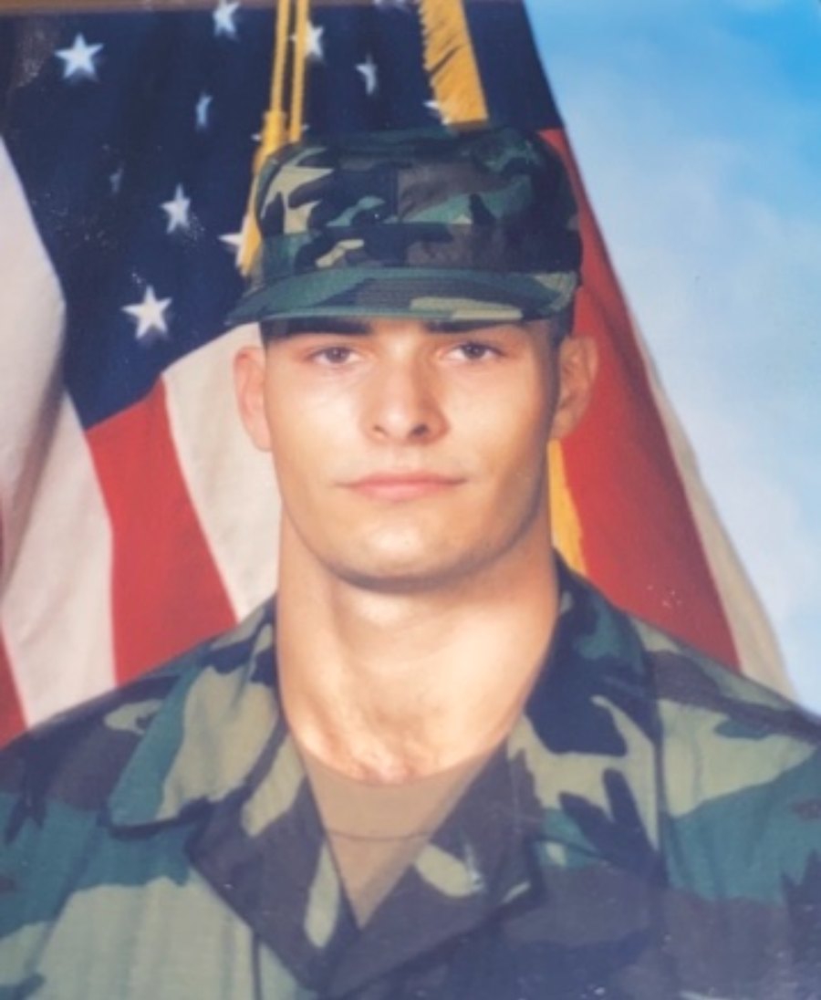 Murph in his U.S. Army uniform, standing in front of the American flag