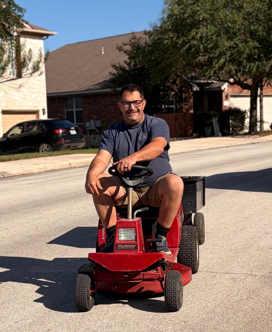 Murph riding a red Murray mower down a San Antonio street